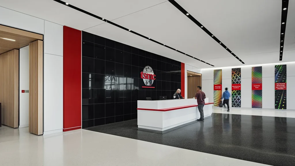 Interno di una fabbrica TSMC: due uomini sono alla reception della struttura in Arizona, sullo sfondo gli ingressi della fab.